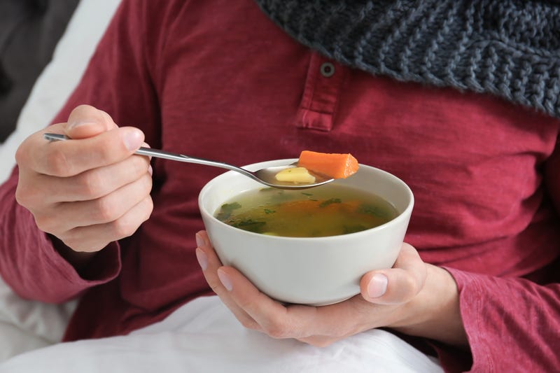 A man holding a bowl of soup and a spoon