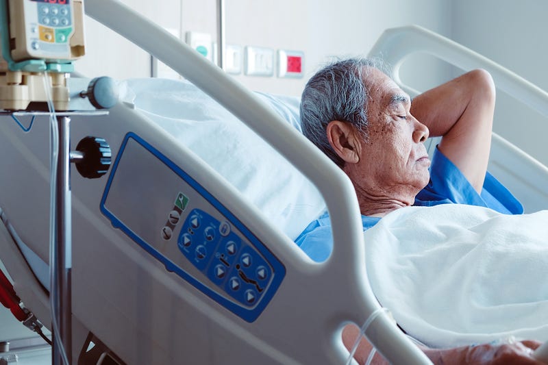 An old man lies in a hospital bed