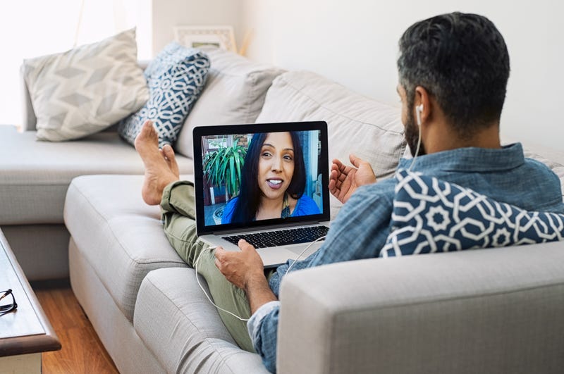 A man video chats with a woman while sitting on his couch