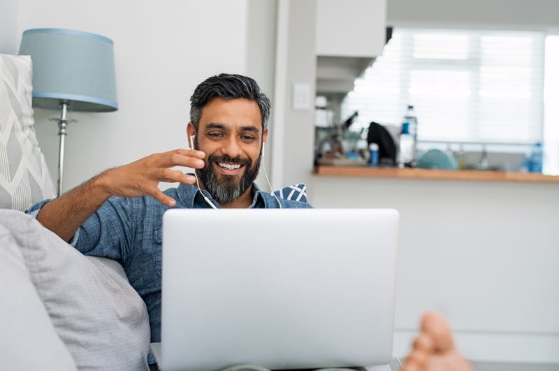 A man smiles at his laptop