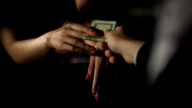 Businessman in car giving money to prostitute.