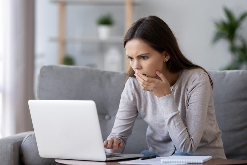 A woman looks at her computer in shock