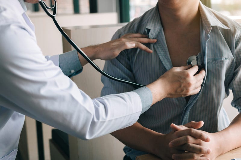 A doctor uses a stethoscope to listen their patient's heart.