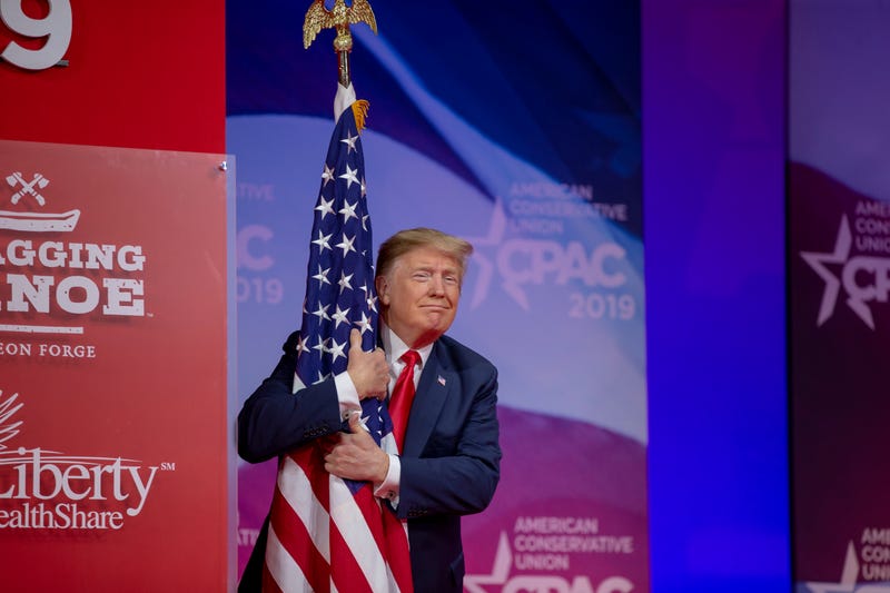 U.S. President Donald Trump hugs the U.S. flag during CPAC 2019 on March 02, 2019 in National Harbor, Maryland