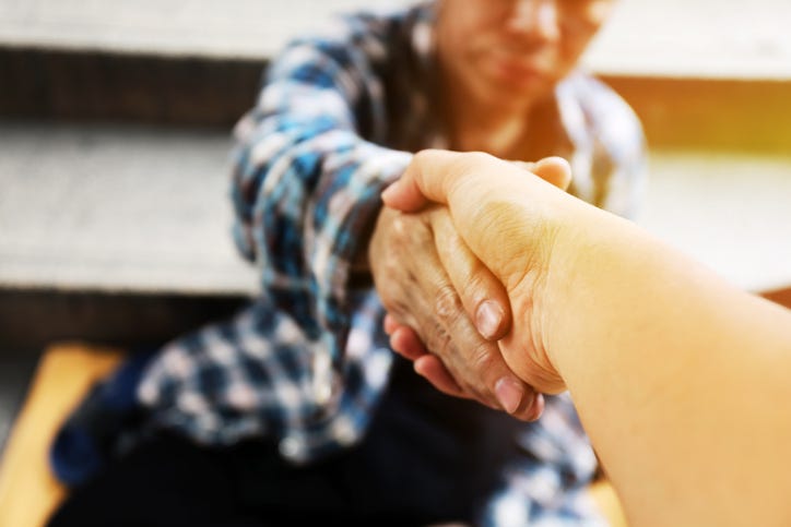 Close-up handshake for help homeless man on walking street