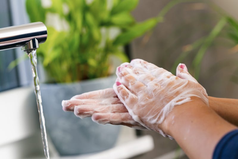 A pair of soapy hands by a running tap