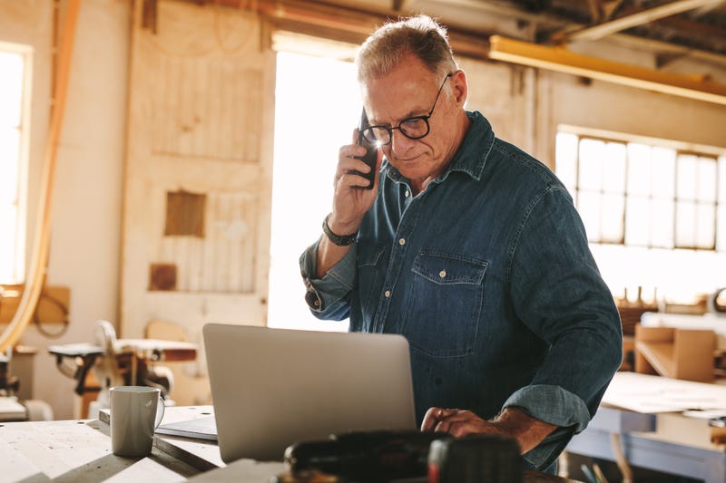 carpenter browses computer and talks on the phone