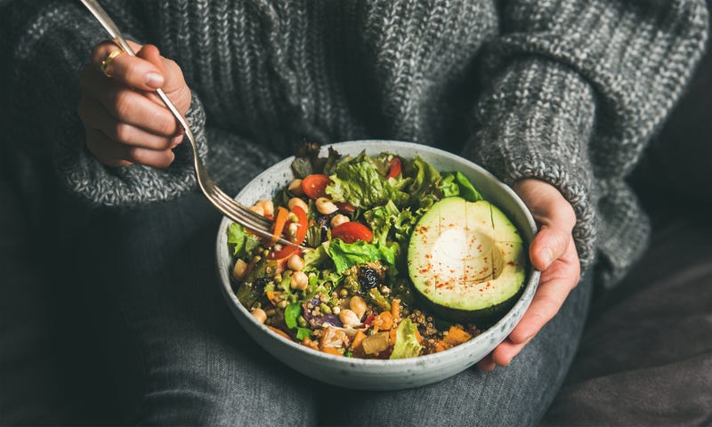 A woman holds a large plant-based bowl