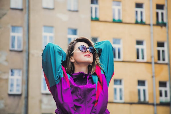 Young woman in 90s jacket posing in front of building