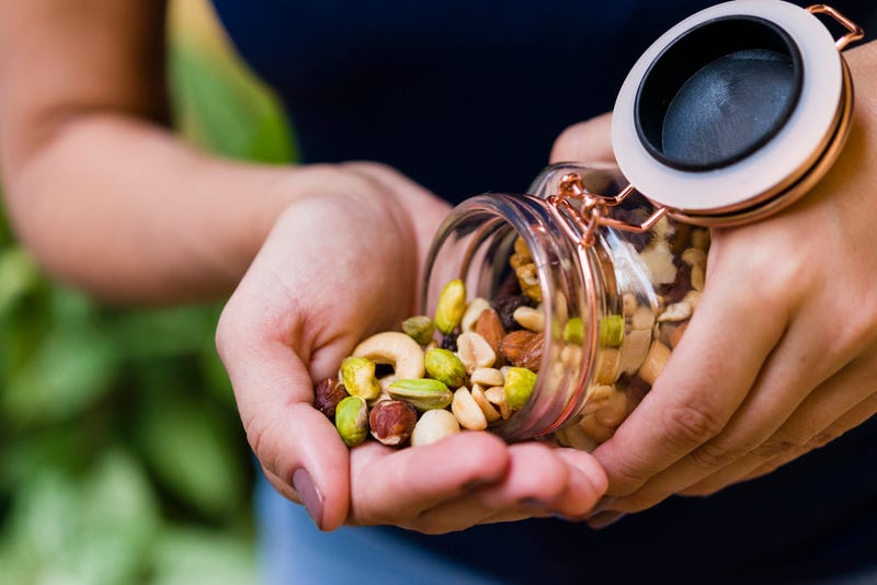 Woman's hand holding glass hermetic pot with mix of nuts