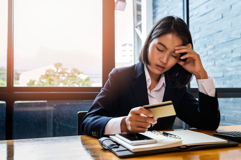 A woman looking anxious with a credit card and bills