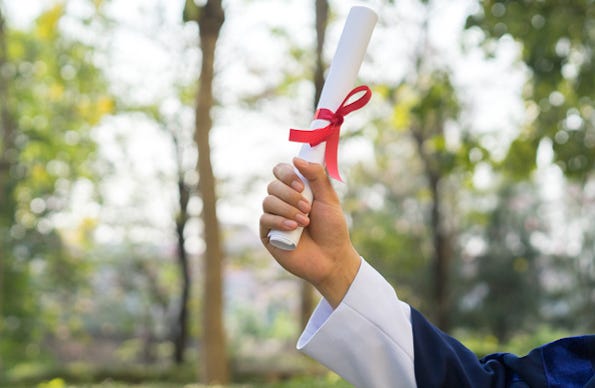 Hand wearing graduation robes holding diploma