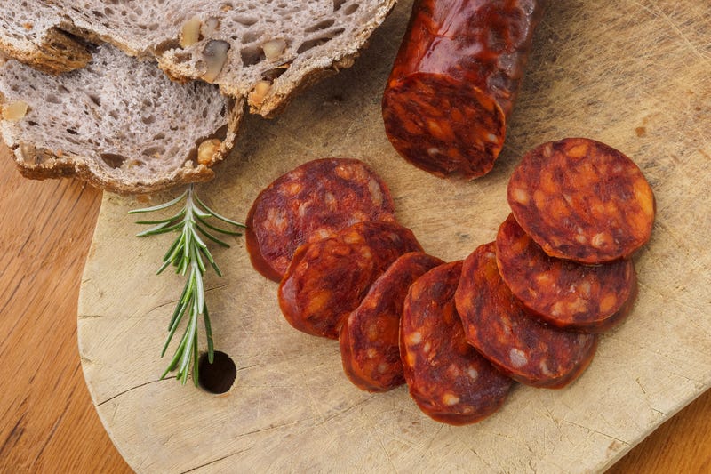 Iberian chorizo, Spanish chorizo or Spanish sausage cut into slices on a wooden board with rustic bread.