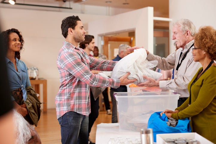 A man hands over a stack of clothes to a volunteer