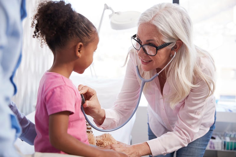 A doctor checks the heart rate of a young girl