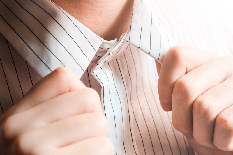 A man's hands adjust the collar of a button-up shirt
