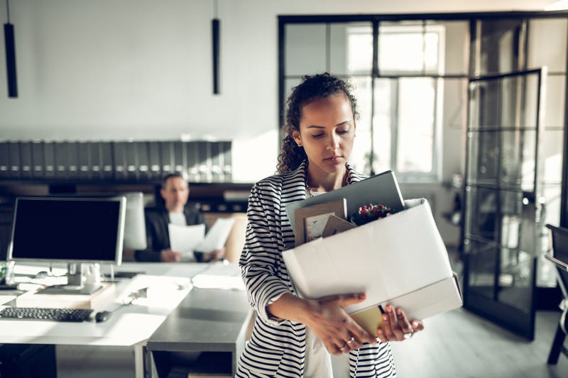 A woman leaves an office with her things