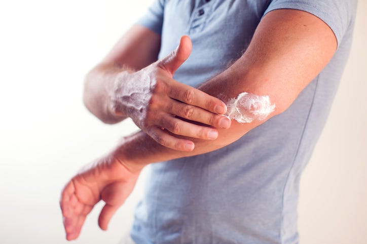 Man applies cream on dry elbow