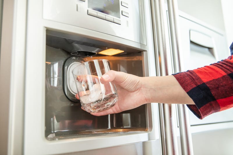 A man gets water from an external water dispenser on a fridge