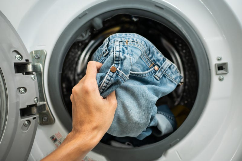 A hand pulling jeans out of a dryer