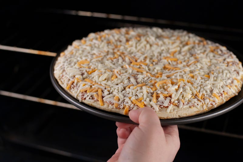 putting a frozen pizza into the oven