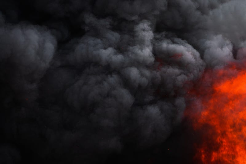 Dangerous red flames of strong fire and dramatic black clouds of smoke.