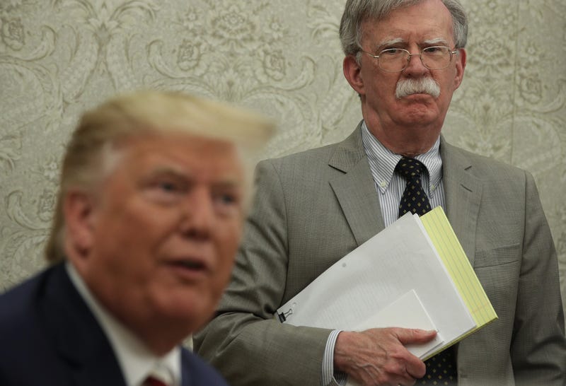 President Donald Trump speaks to members of the media as National Security Adviser John Bolton listens during a meeting with President of Romania Klaus Iohannis in the Oval Office of the White House August 20, 2019 in Washington, DC.