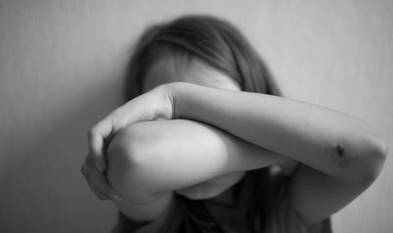 Little girl covers her face with hands