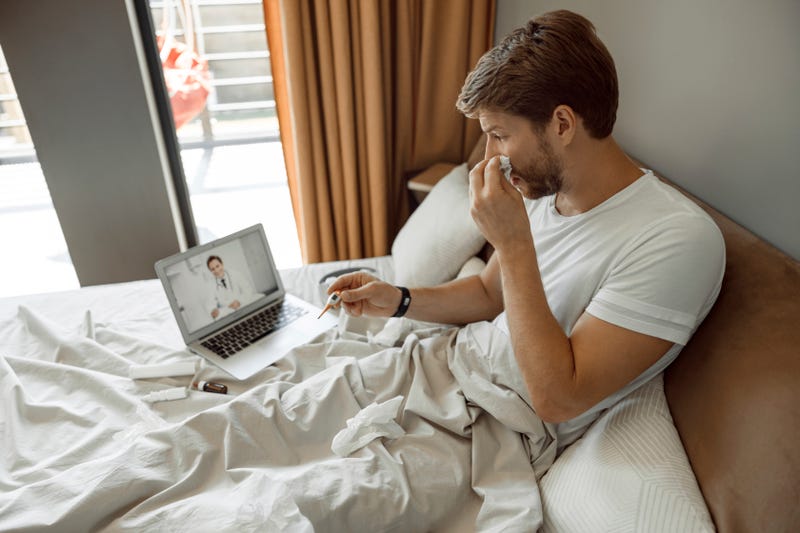 A sick man conferences with a doctor over video chat from his bed