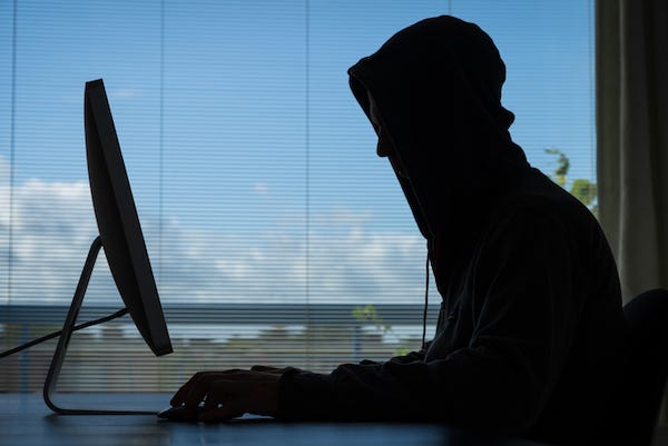 Hacker doing his crime on a desktop computer in broad daylight