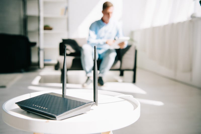 A Wifi router in the foreground, with a man on a laptop in the background