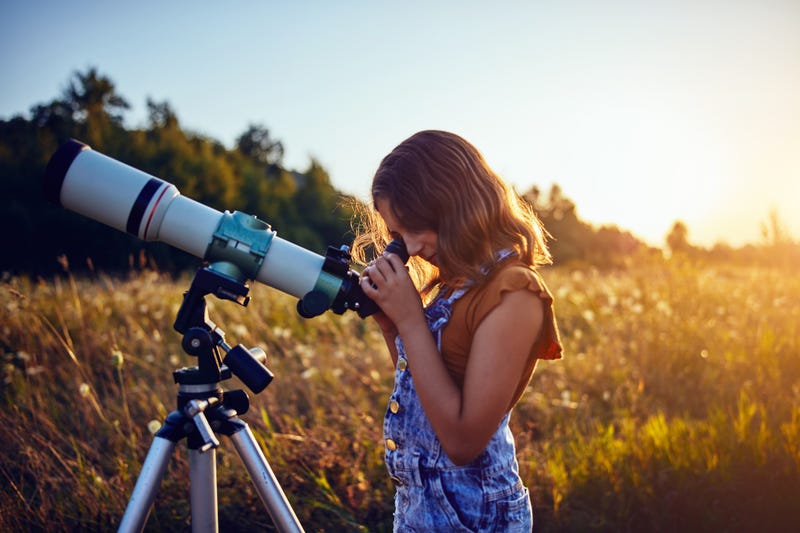 Little girl using telescope 