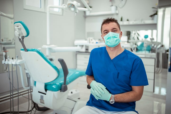 dentist with surgical mask sitting in office