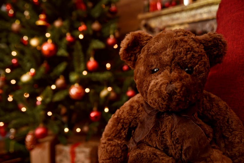 teddy bear sitting in front of a Christmas tree