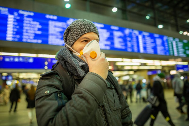 A man in a medical face mask stands in an airport