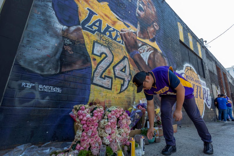 A man places a candle near a mural for former Los Angeles Lakers basketball star Kobe Bryant during the official memorial ceremony for him and his daughter, Gianna.