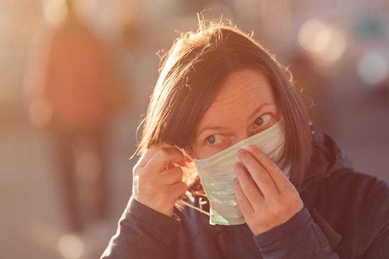 A woman in public puts on a medical face mask