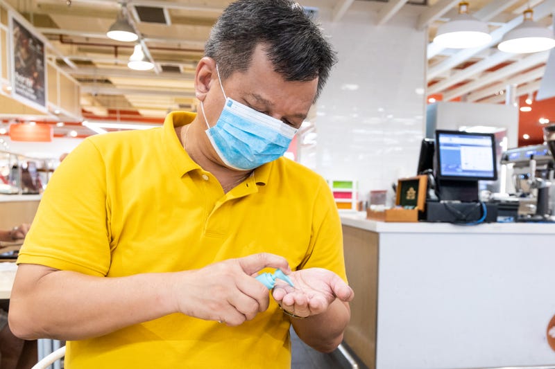 A man in a face mask applies hand sanitizer