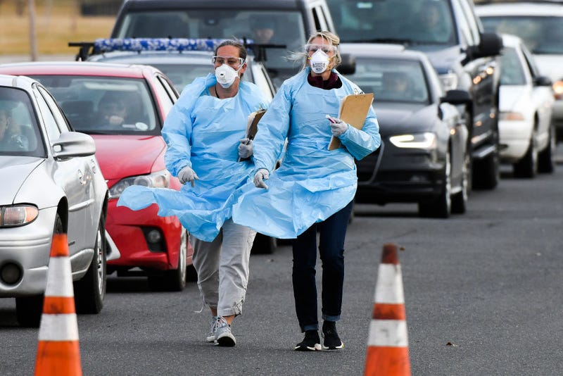 Healthcare workers from the Colorado Department of Public Health and Environment check in with people waiting to be tested for COVID-19 at the state's first drive-up testing center on March 12, 2020 in Denver, Colorado.