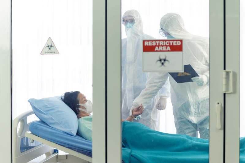 Doctors in hazmat suits inspect a sick patient in a quarantine area