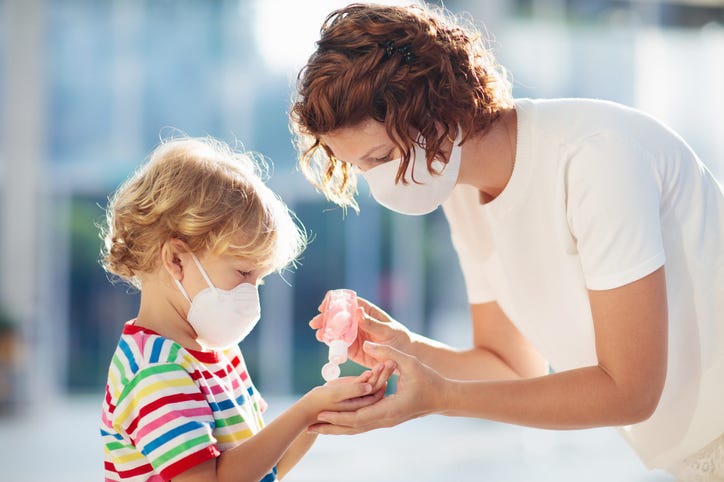 mother giving child hand sanitizer