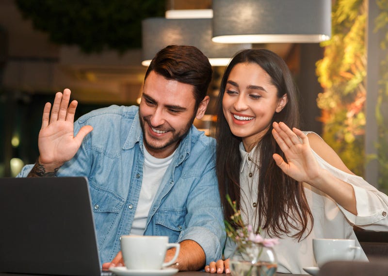 A couple wave to a computer