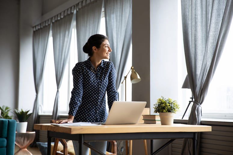 Young woman looking out window of home office