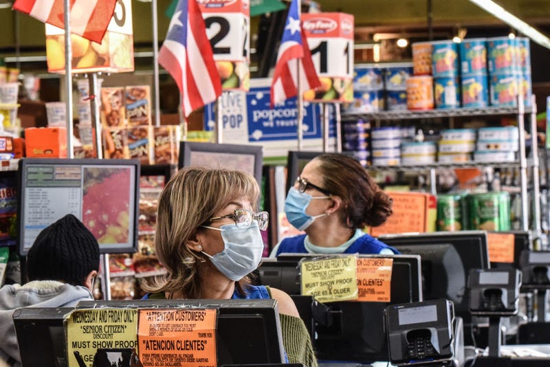 Cashiers wearing protective masks work in a grocery store in the Bushwick neighborhood of Brooklyn