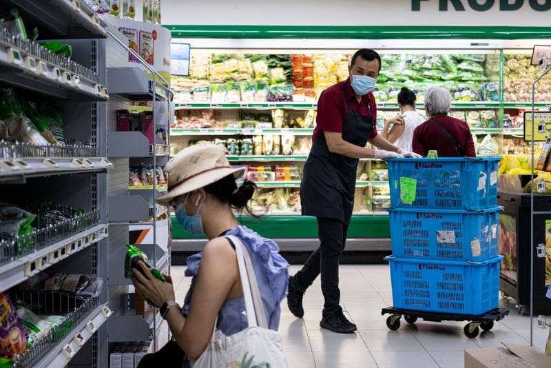 People wearing protective masks shop in a supermarket on April 6, 2020 in Singapore, a day before a 'circuit breaker' takes effect. The Singapore government will close all schools and most workplaces and limit social interactions and movement outside homes for at least a month to stem the spike in local coronavirus cases.