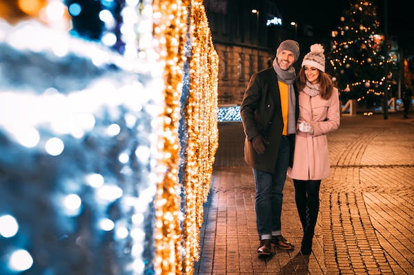 Happy couple walks on a street decorated for Christmas