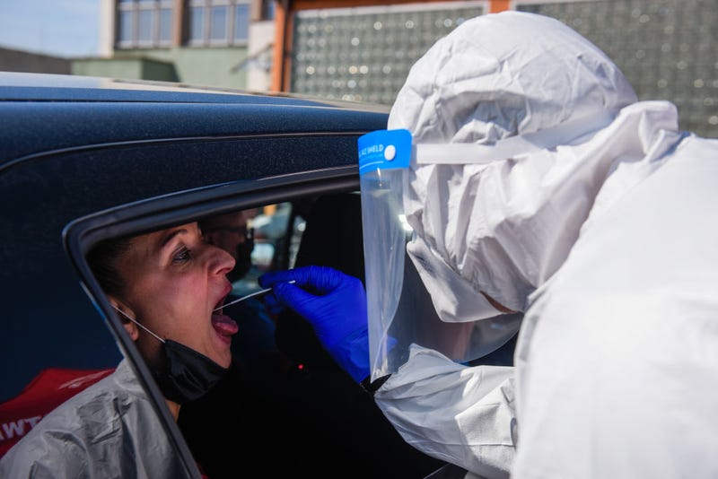 A health worker wears a protective suit, gloves, mask and a face shield as she takes a saliva sample