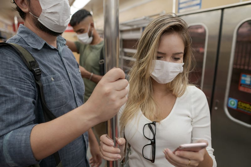 man and woman ride the train wearing face masks