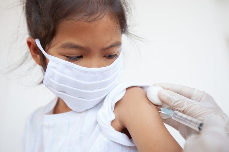 girl wearing face mask gets vaccine