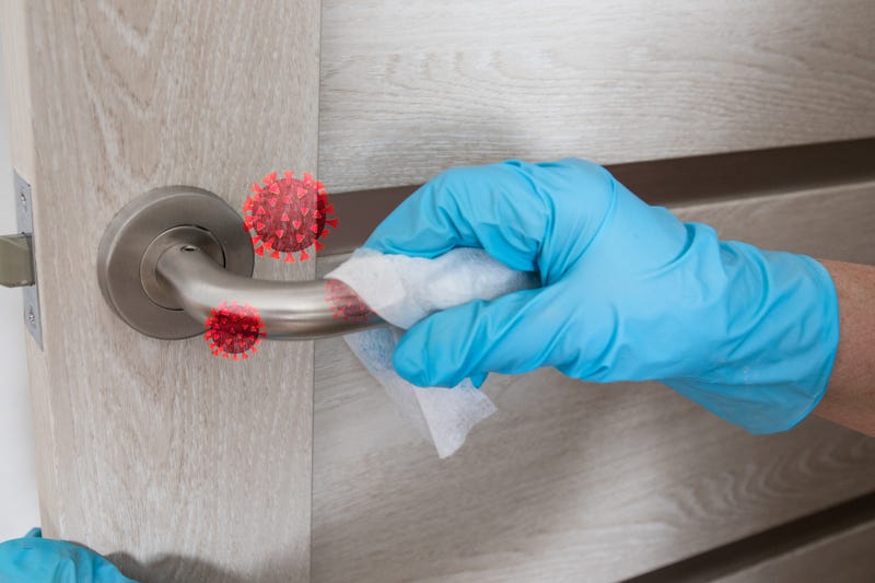 Wiping door knob with antibacterial disinfecting wipe for killing coronavirus.